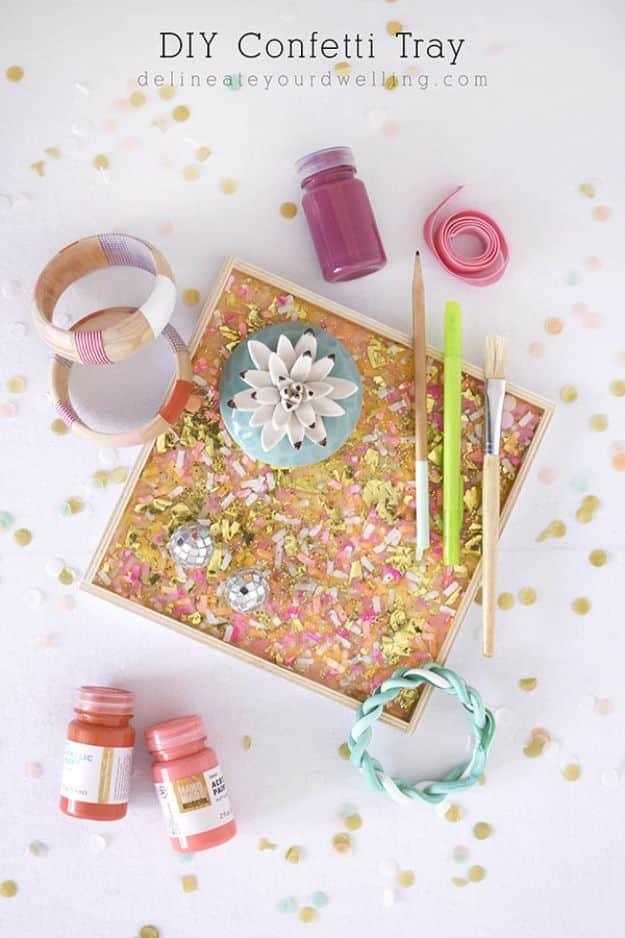 Wooden tray filled with gold and pink confetti under a glossy clear coating with jars and craft supplies