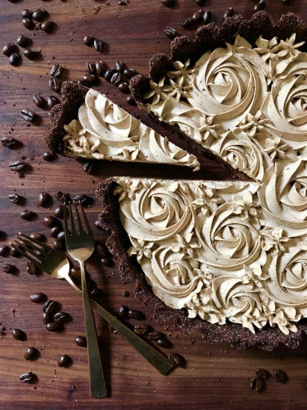 Dark chocolate tart covered in piped espresso whipped cream rosettes with coffee beans and forks alongside