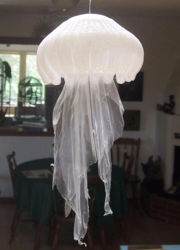 Jellyfish hung from a ceiling, made from a pleated foam fruit tray with long ragged plastic bag strips trailing below