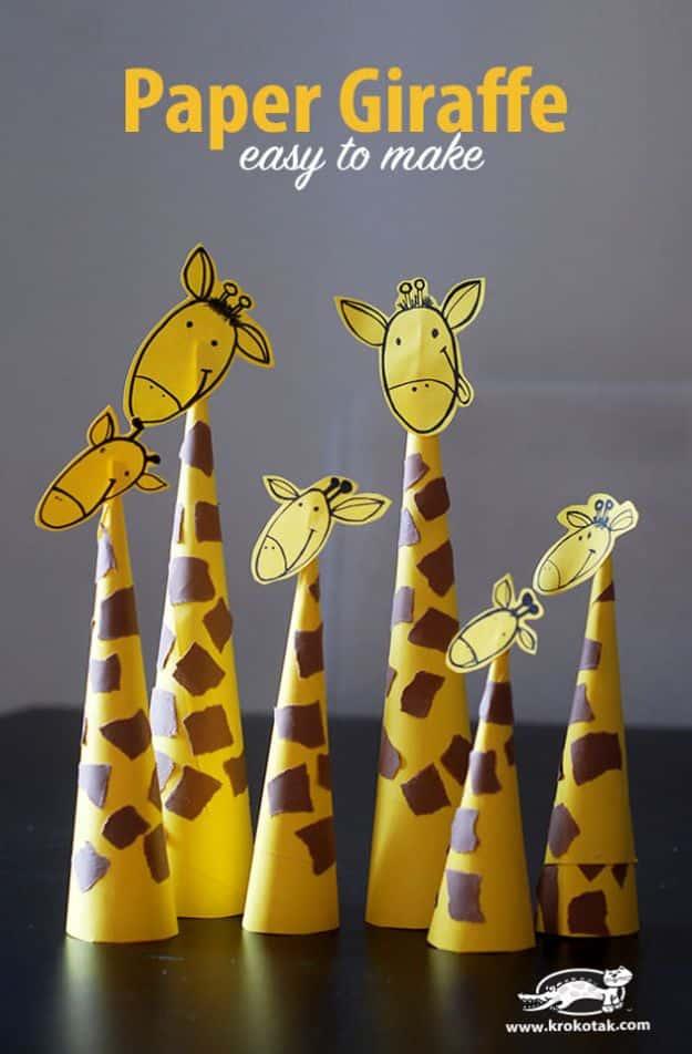 Five paper cone giraffes of different heights with brown spots and folded heads, standing in a row on a dark surface