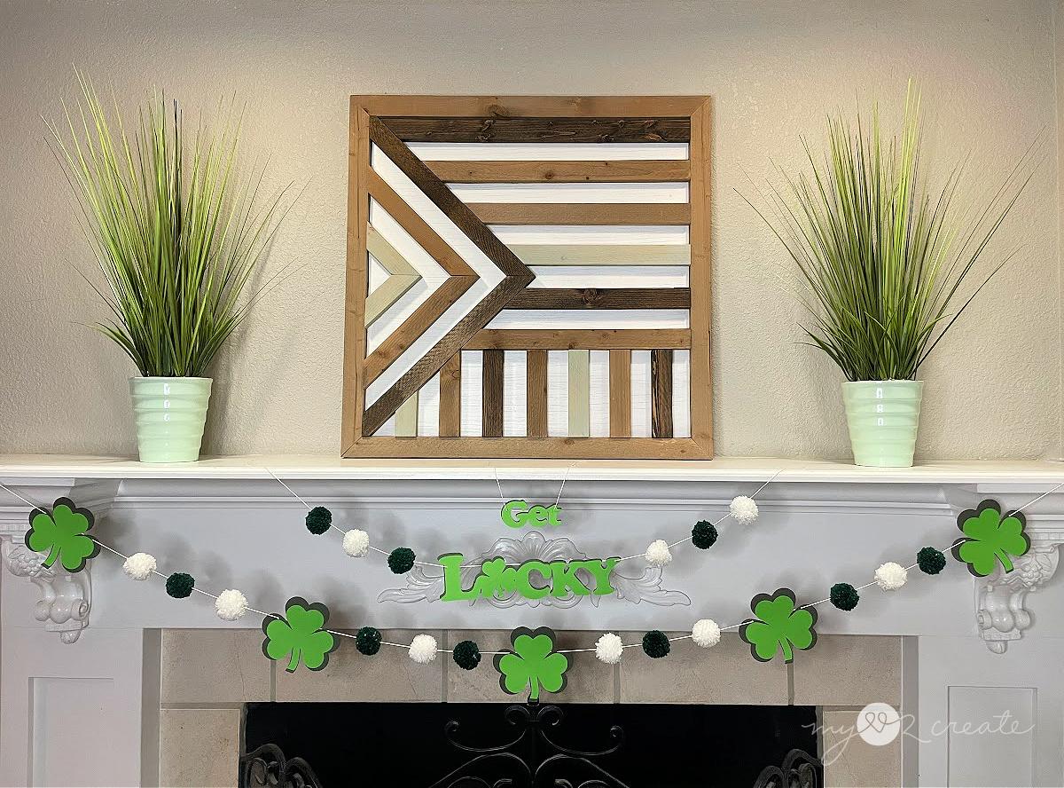 St. Patrick's Day decor, a shamrock and pom pom garland with a Get Lucky sign strung across a white mantel