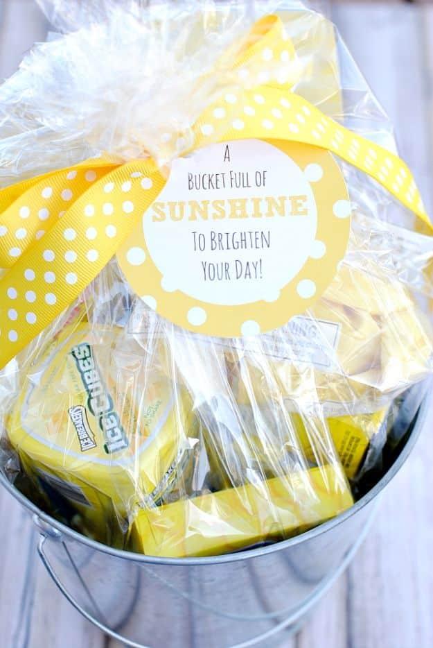 A metal bucket filled with yellow gifts and treats with a printable sunshine tag, a cheerful DIY gift idea