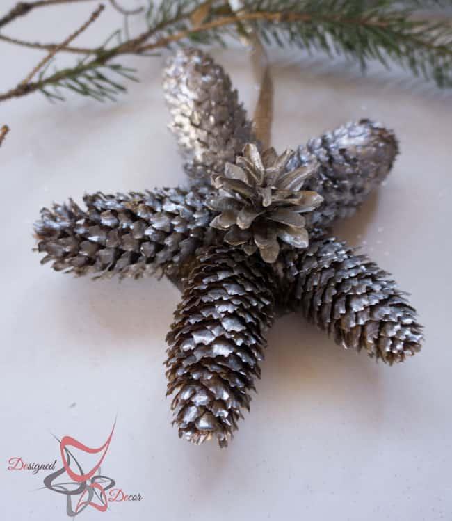 Star shaped Christmas ornament made from five pine cones spray painted metallic silver with a small cone glued in the center