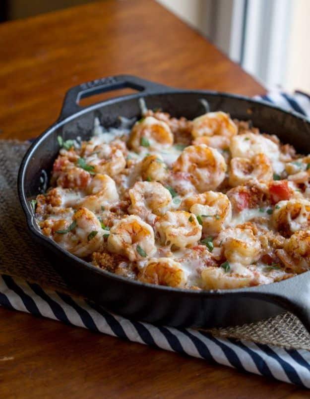 Cajun shrimp quinoa casserole in a cast iron skillet with melted fontina cheese and fresh cilantro on top