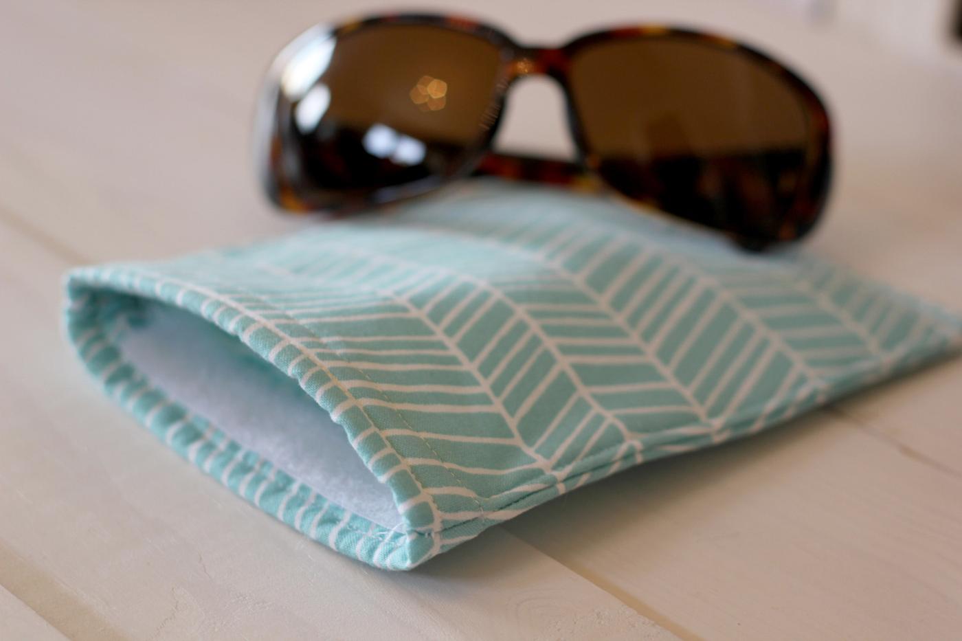 Padded sunglasses case in a pale blue chevron print fabric with tortoiseshell sunglasses resting on top
