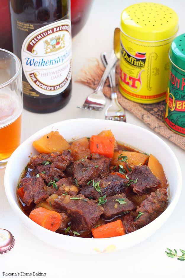 Beer braised beef with carrots and potatoes in a white bowl, a beer bottle and spice jars behind it.