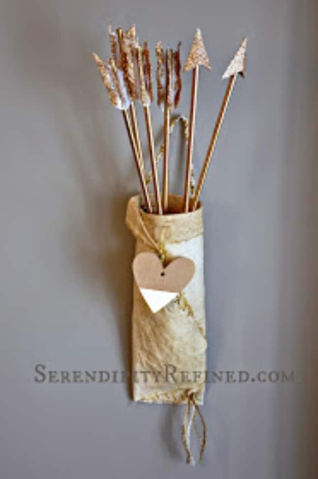 Handmade cupid arrows standing in a fabric wrapped quiver leaning against a wall as party decor for Valentine's Day