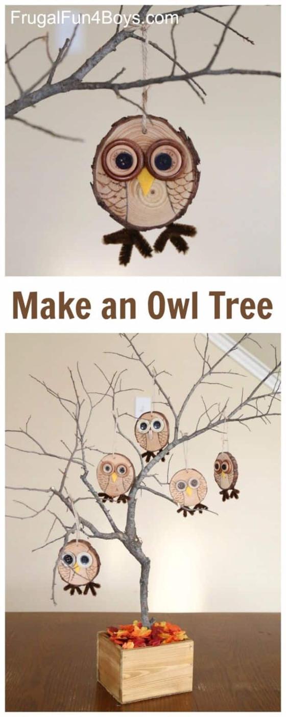 Wood slice owl ornaments with layered button eyes and felt beaks hanging on a bare branch tree in a wood box