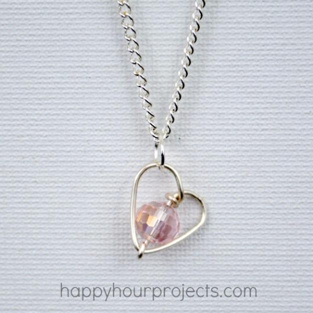 Wire wrapped heart pendant on a chain resting on a white surface, a handmade Valentine's necklace for Valentine's Day