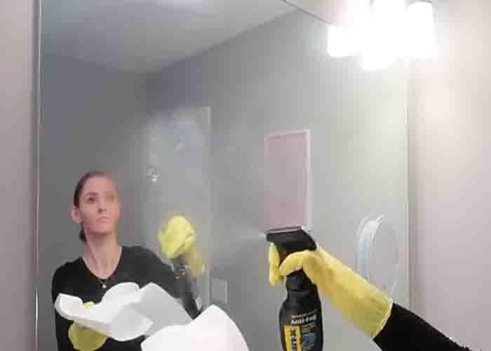 Spraying anti-fog on the bathroom glass mirror