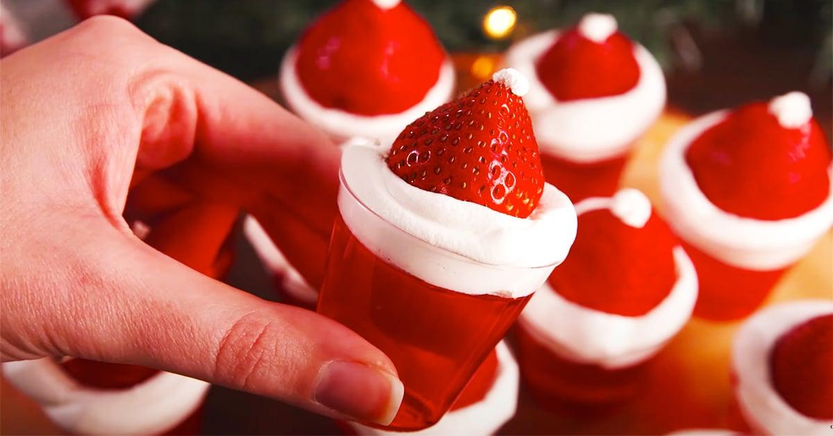 Santa hat jello shots topped with whipped cream and an upturned strawberry with a white dot at the tip