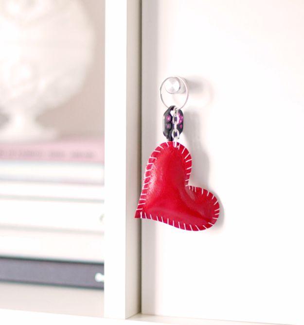 A hand stitched leather heart key ring hanging on a chain, a small handmade Valentine's Day gift for her