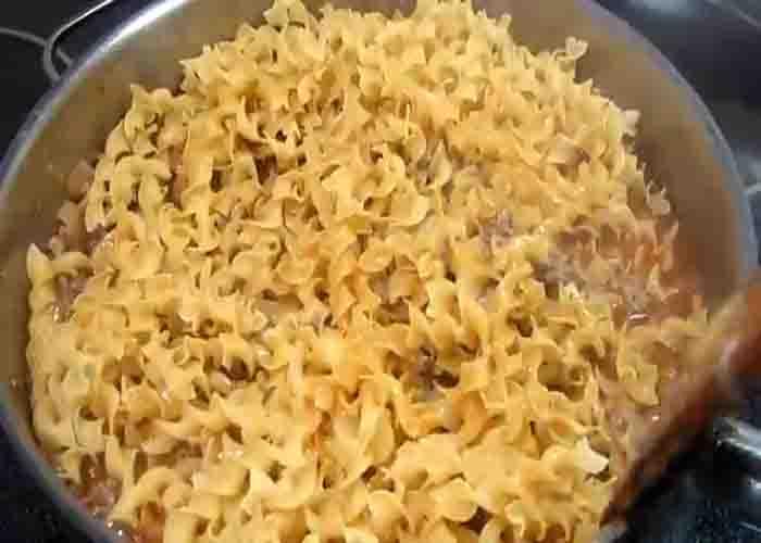 Stirring in the egg noodles into the ground beef mixture