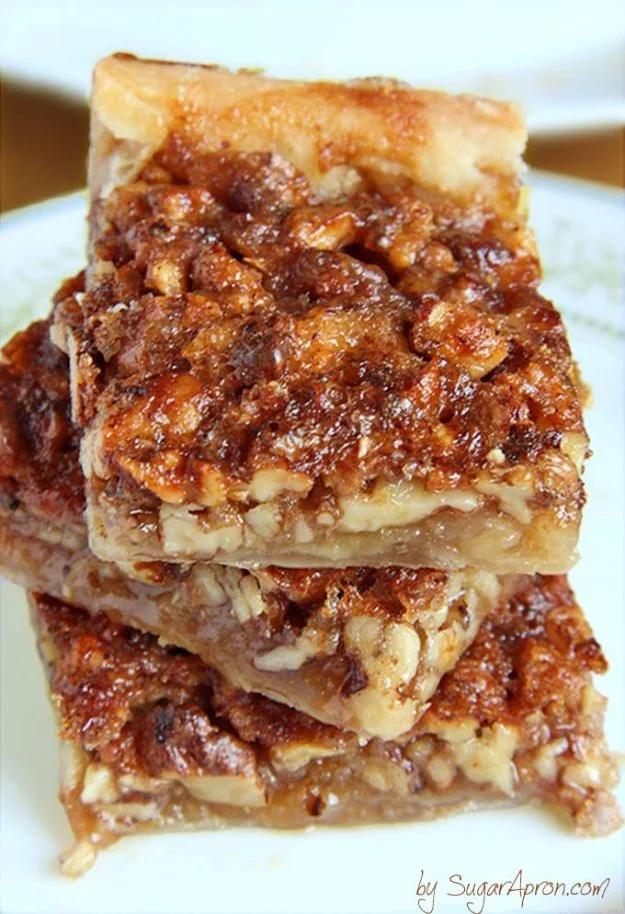 Easy pecan pie bars with a crescent roll crust, cut into squares and topped with toasted chopped pecans