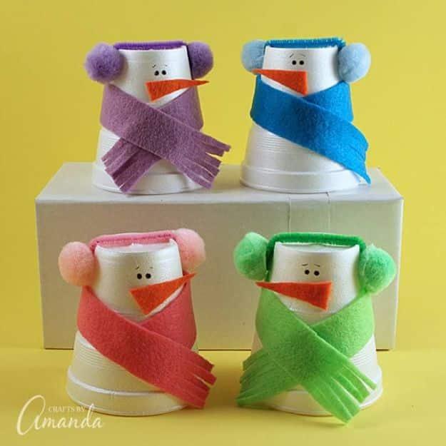 Four upside down foam cup snowmen with purple, blue, pink and green felt scarves and pom pom earmuffs