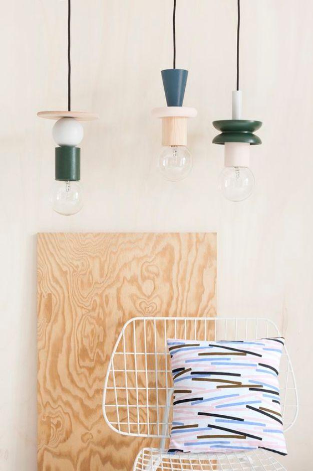 Three pendant lights with painted wood and polystyrene collars hung over a plywood panel, a beginner decor idea
