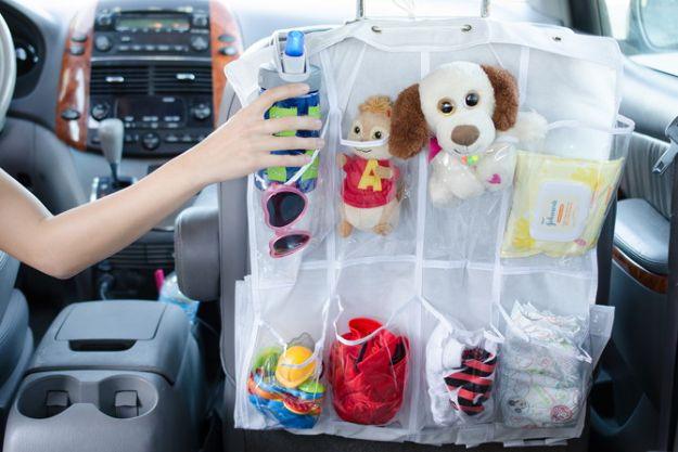 Back seat pocket organizer, a white hanging shoe organizer on a car seat holding toys, wipes, sunglasses and a bottle