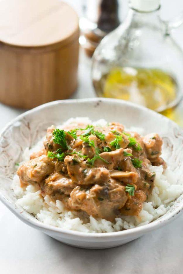 Healthy chicken stroganoff served over white rice in a bowl, chicken and mushrooms in a creamy sauce with parsley