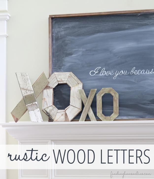 Rustic stained wood letters spelling My Valentine leaning on a shelf beside greenery and a candle for Valentine's Day