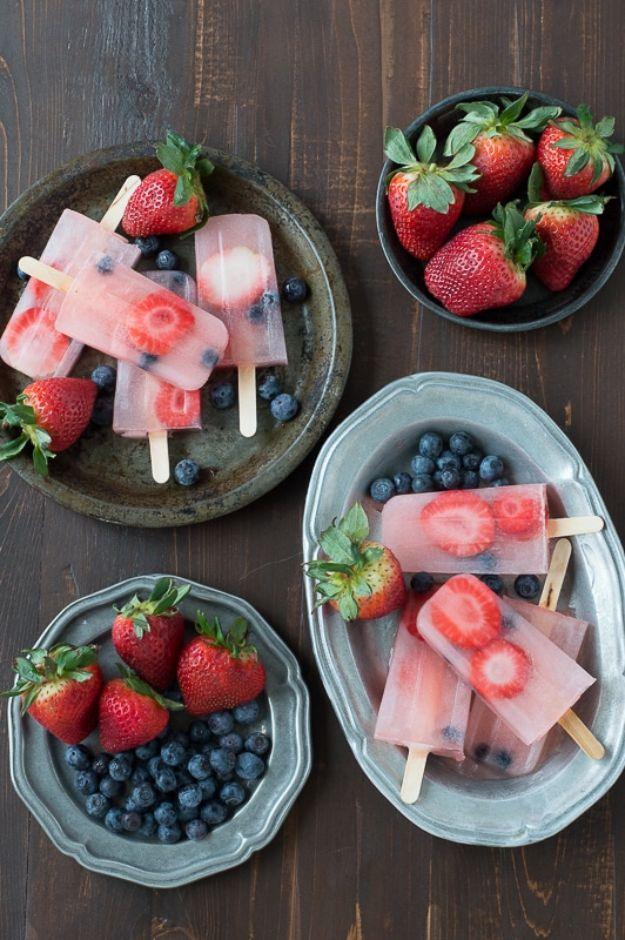 Berry lemonade popsicles frozen with sliced strawberries and blueberries suspended inside, an easy frozen treat