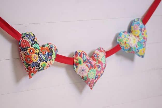 Puffy heart bunting, three stuffed hearts in bright multicolor florals strung on red bias binding on white wood