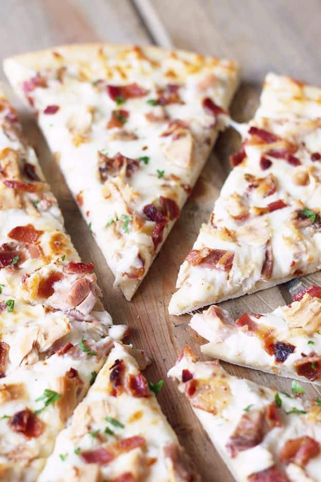 Chicken bacon ranch pizza cut into slices with white ranch sauce, chicken and bacon on a wooden board
