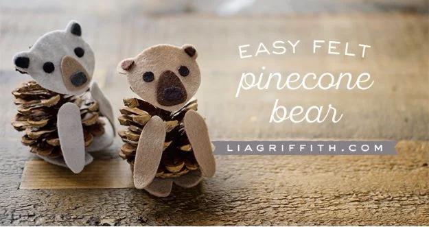 Two small bears made from pine cones with brown and cream felt heads, ears and feet, standing on a weathered wooden plank