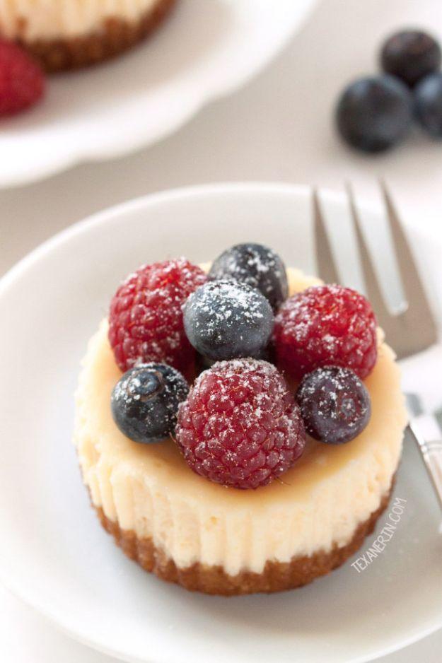 Gluten free mini cheesecakes in muffin liners topped with fresh berries and a dusting of powdered sugar