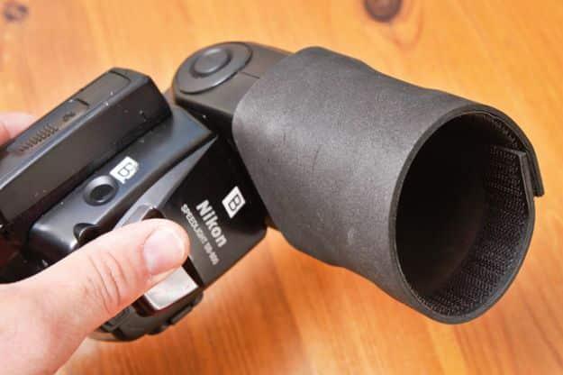 Boost your flash with foam and Velcro, a hand holding a Nikon flashgun fitted with a black craft foam snoot