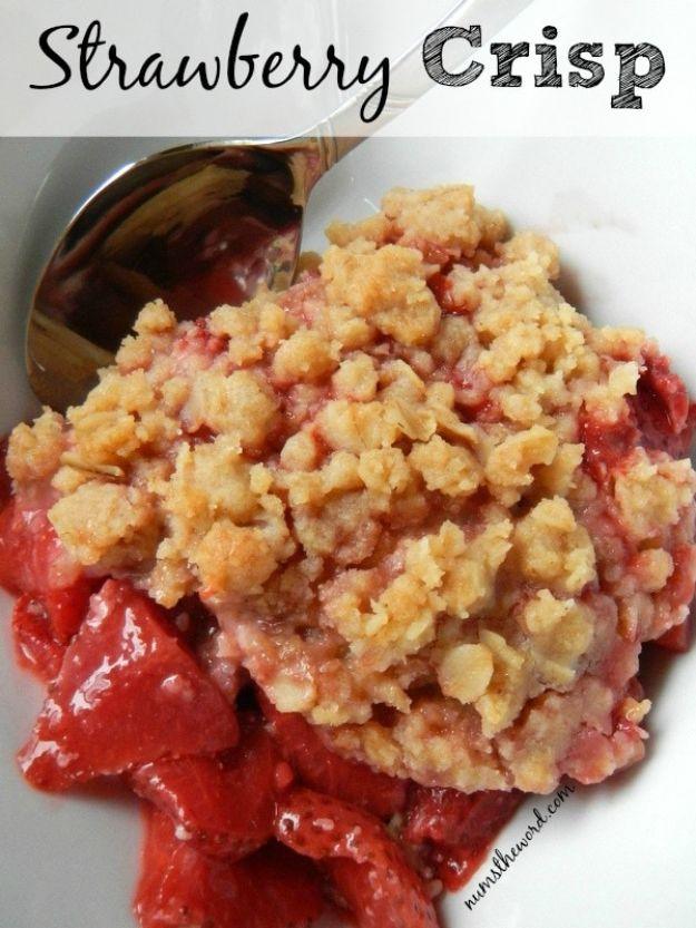 Strawberry crisp on a white plate with a spoon resting in it, pale oat crumble over soft red berry filling
