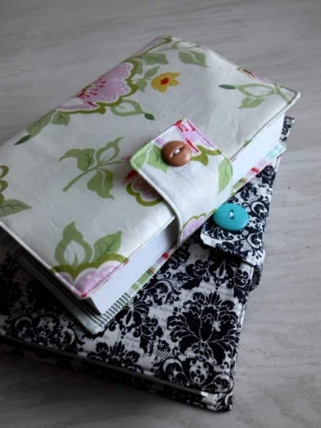 Two fabric covered journals, one in a green and pink floral with a button loop closure, one in black damask