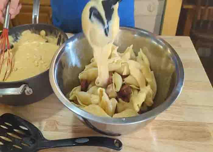 Tossing the giant mac and cheese with the creamy sauce