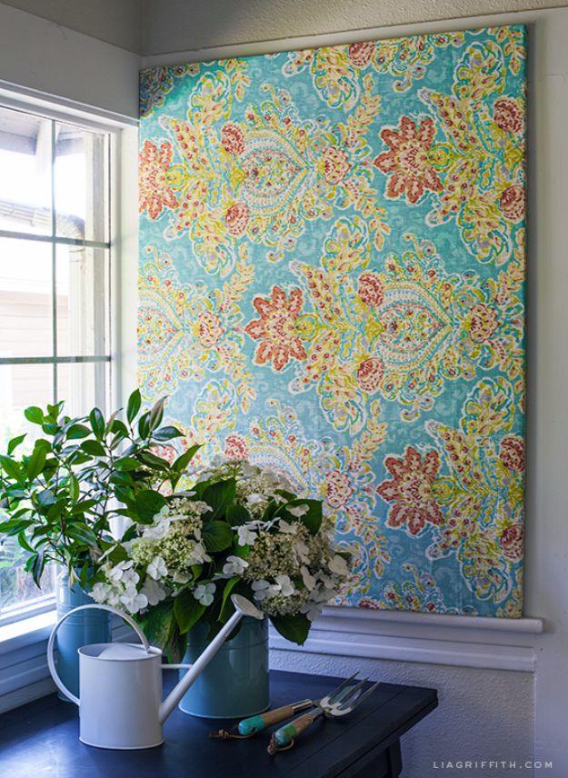 Large teal and orange paisley fabric stretched over a frame covering a window above a blue potting table with hydrangeas