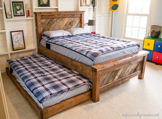 Farmhouse pallet bed frame with a chevron headboard and a rolling trundle bed pulled out underneath it