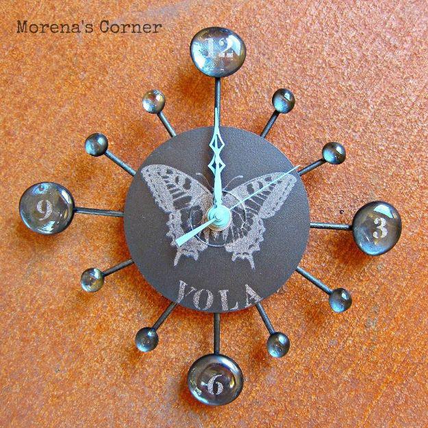 Wall clock made from an old CD painted dark grey with a silver butterfly stencil and glass gem numbers