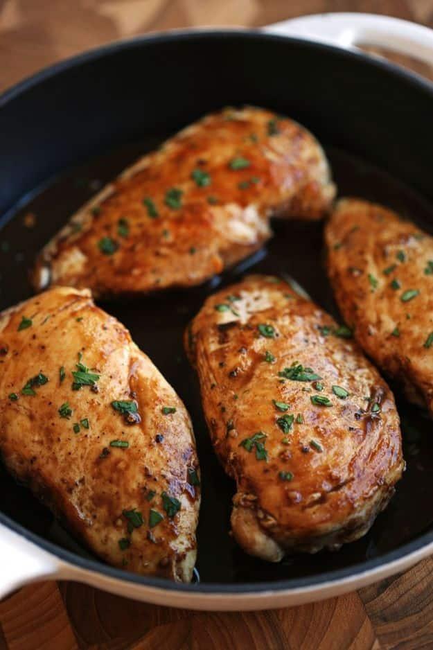 Maple balsamic herb chicken breasts browned in a black skillet, glazed dark at the edges and scattered with herbs