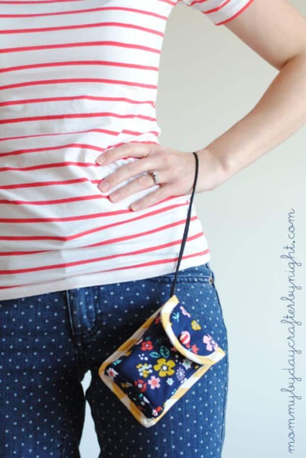 Camera cozy sewn from a navy floral fat quarter with yellow binding, worn on a cord over a red striped top