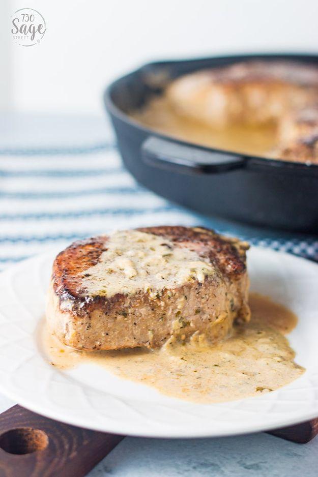 Keto creamy ranch pork chop on a white plate covered in a pale sauce with a cast iron skillet behind it