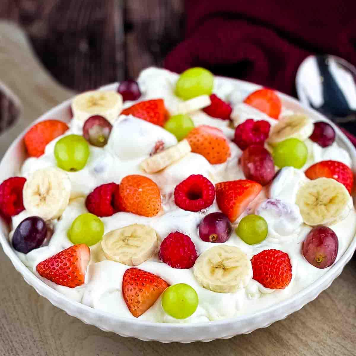 Creamy fruit salad with Cool Whip and vanilla pudding folded through strawberries, grapes and bananas