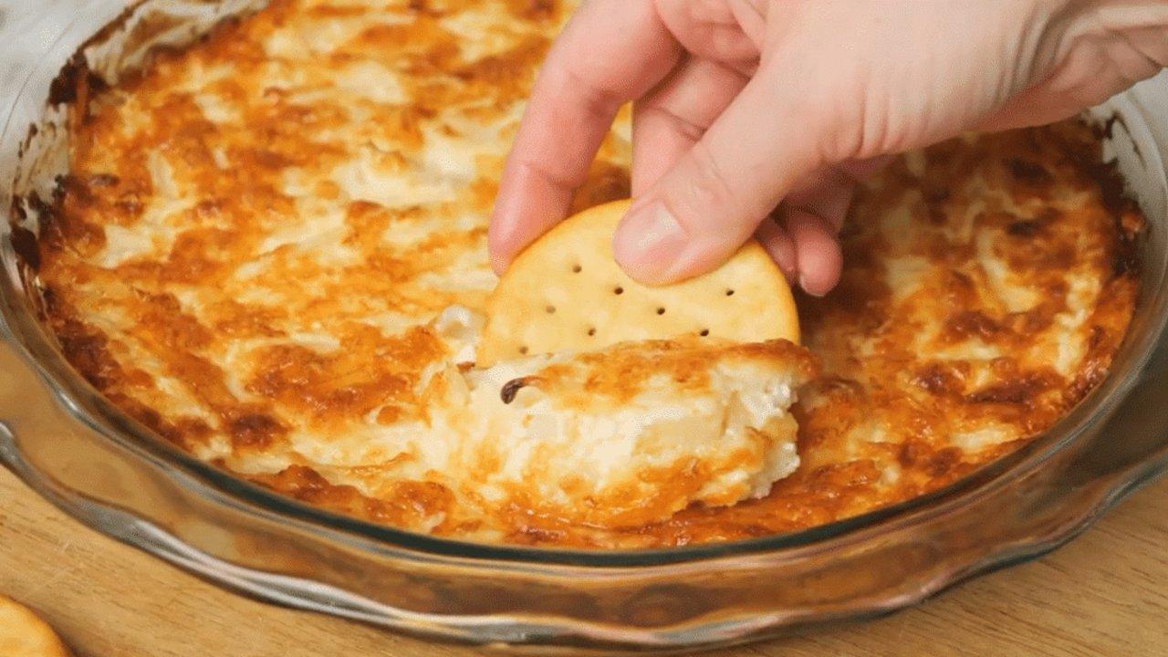 Easy hot onion dip baked golden and bubbling in a dish with Swiss cheese and thin sliced yellow onion