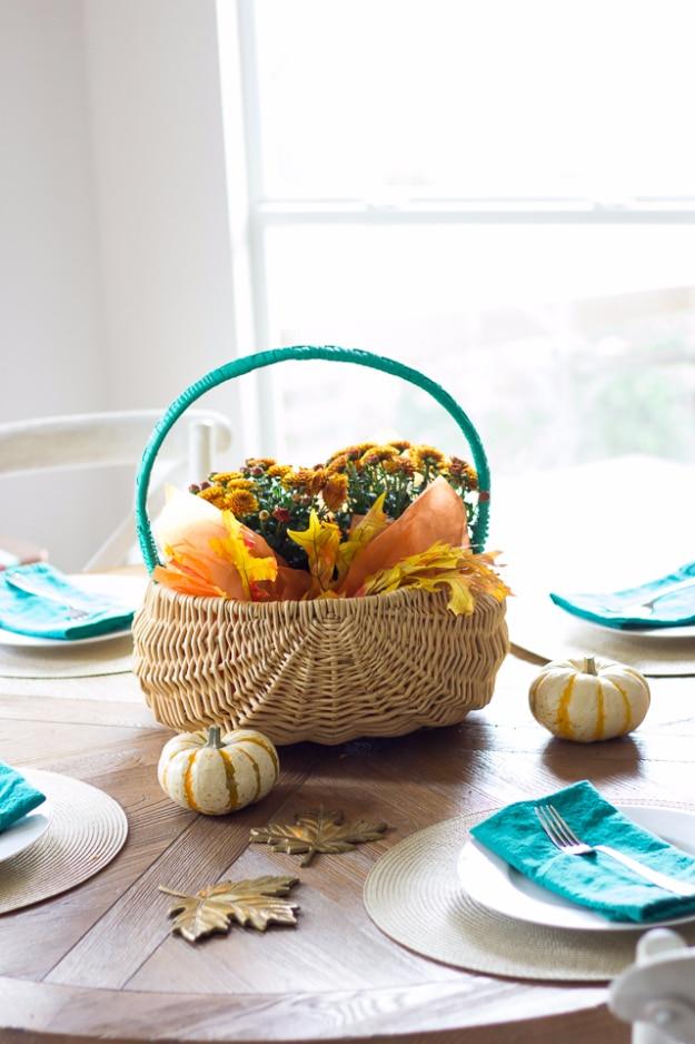 Thanksgiving centerpiece made from a repurposed Easter basket filled with fall flowers and artificial autumn leaves