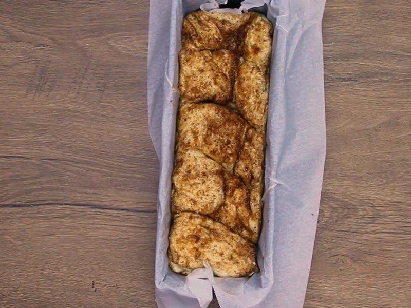 Cinnamon sugar coated dough pieces layered in a parchment lined loaf pan