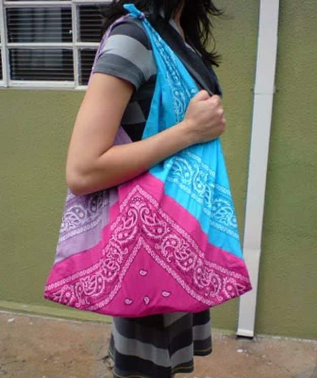 Cute bandana shoulder bag sewing idea, a slouchy turquoise, pink and lavender bag against a green wall