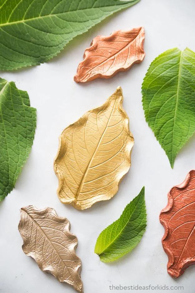 Air dry clay dishes shaped from real leaves and painted in gold, rose gold and bronze beside green leaves