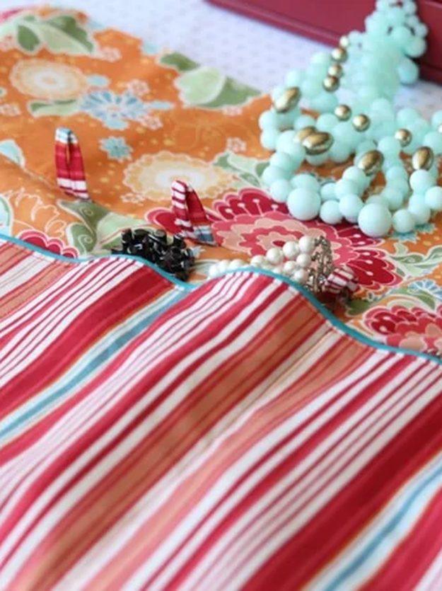 Roll up fabric travel jewelry case with mint beaded, pearl and black necklaces laid across its pockets