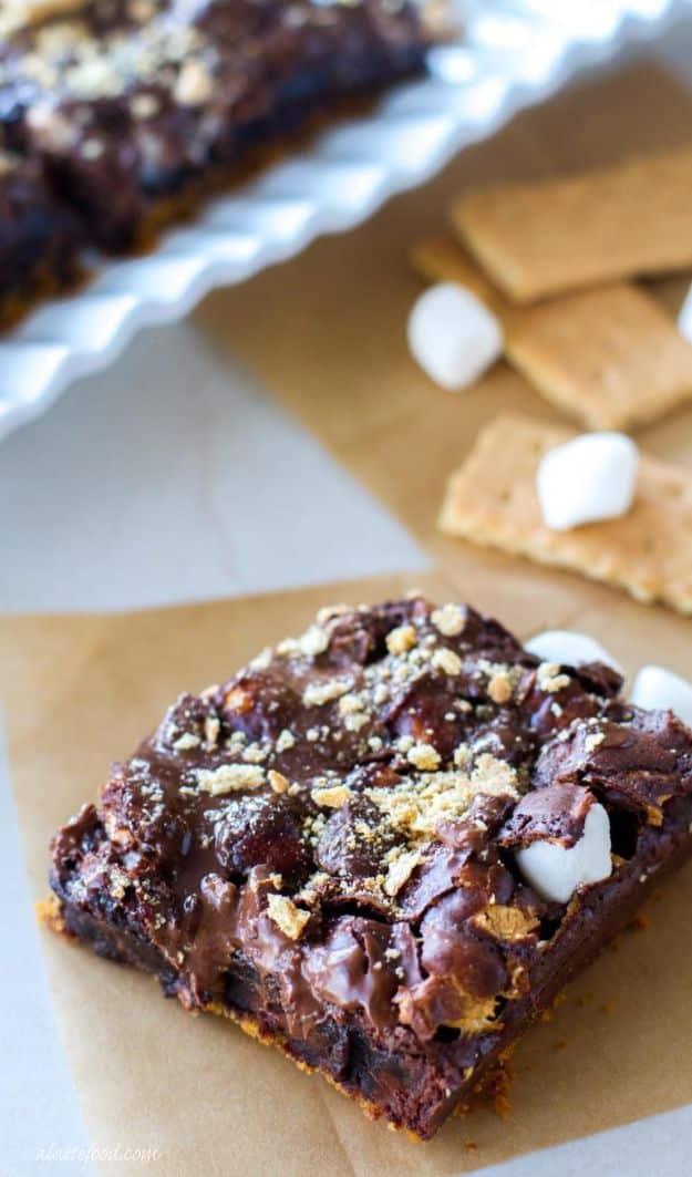 A s'mores brownie on parchment with a graham crust, melted chocolate, mini marshmallows and cracker crumbs