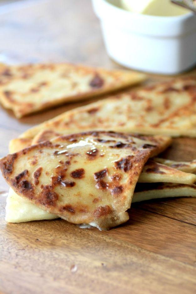 Irish potato scones, triangular pan browned farls stacked on a wooden board with butter melting on top