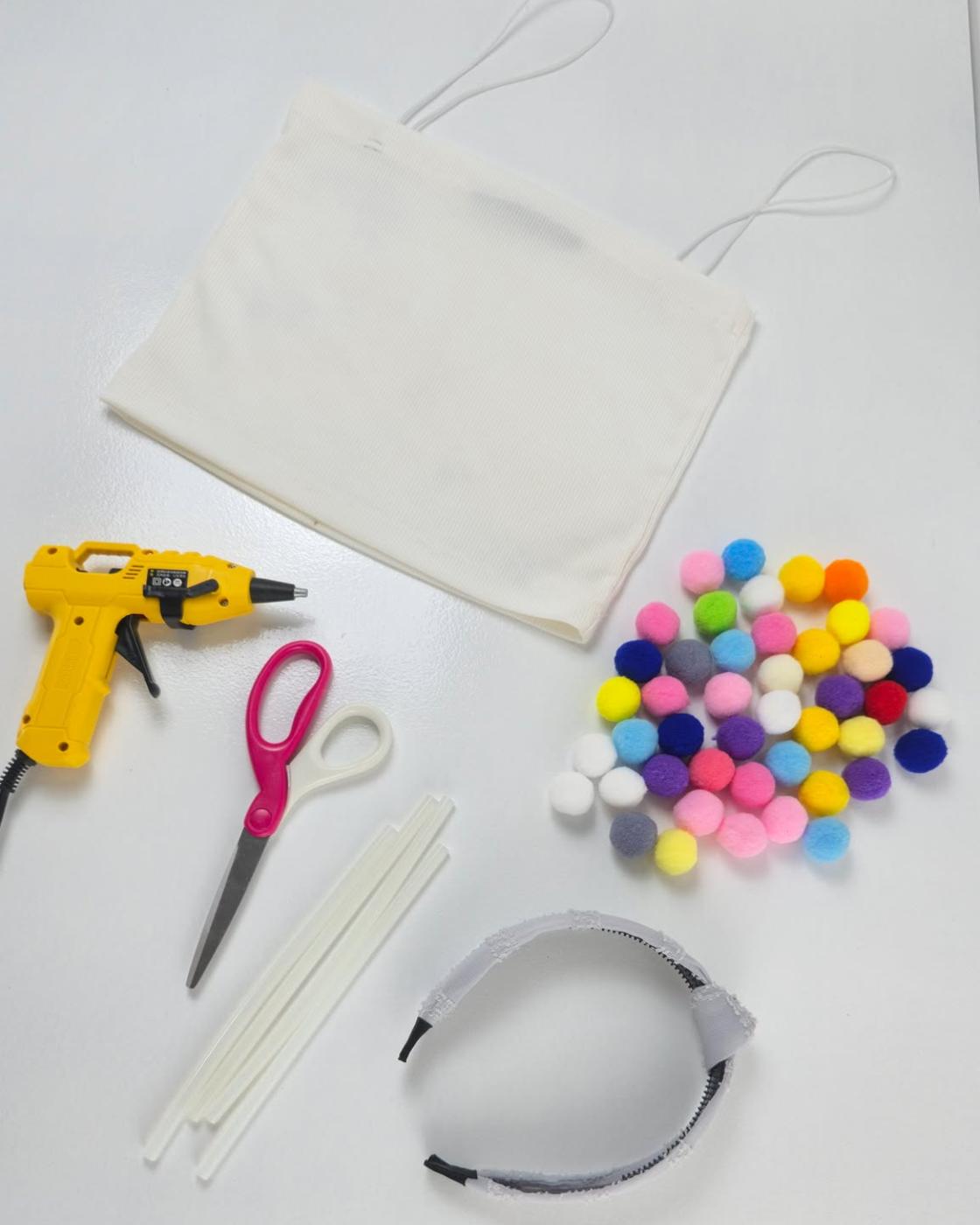 Cheap Costume Ideas - flat lay of supplies, a crop top, glue gun, scissors, pom poms and a plain headband