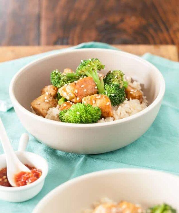 Healthy General Tso's chicken in a pale bowl over white rice with broccoli florets and toasted sesame seeds