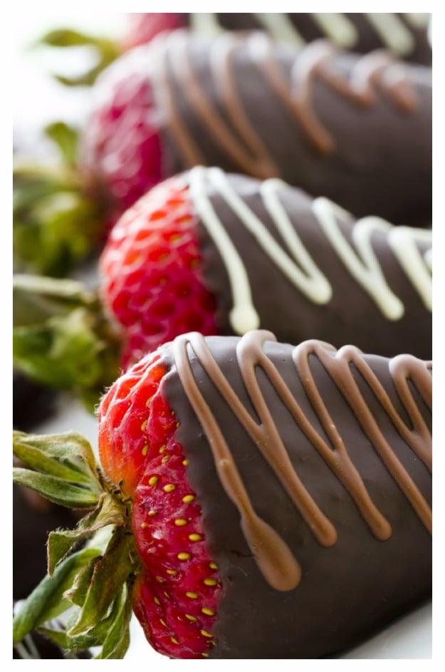 Chocolate covered strawberries with white chocolate drizzle on parchment, a fast last minute dessert idea
